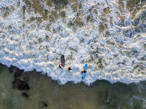 Indonesien, Bali, Luftaufnahme von Dreamland Beach, drei Surfer von oben, lizenzfreies Stockfoto