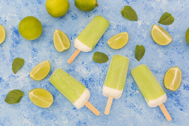 Lime mint popsicles, limes and mint leaves on light blue background - JUNF01259