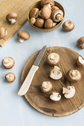 Sliced and whole Crimini Mushrooms on wooden board - JUNF01271