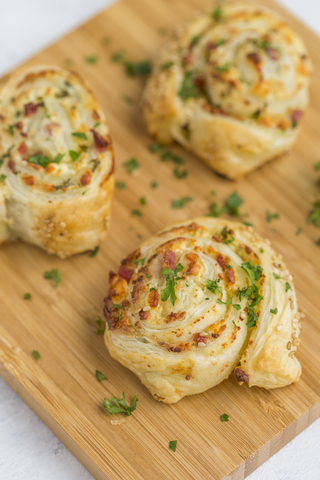 Klebrige Brötchen mit Feta, Frischkäse, Speck und Petersilie auf Holzbrett, lizenzfreies Stockfoto