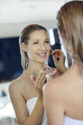 Mirror image of smiling blond woman applying makeup - PNEF00941