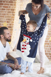 Junge probiert übergroßen Weihnachtspulli mit Eltern im Bett an - ABIF01037