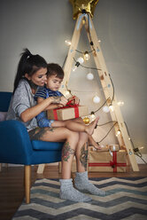 Junge öffnet Weihnachtsgeschenk mit seiner Mutter zu Hause - ABIF01069