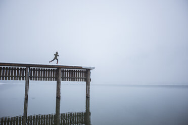 Humorus image of a woman appearing to run off the end of a tall dock into a lake far below. - AURF05504