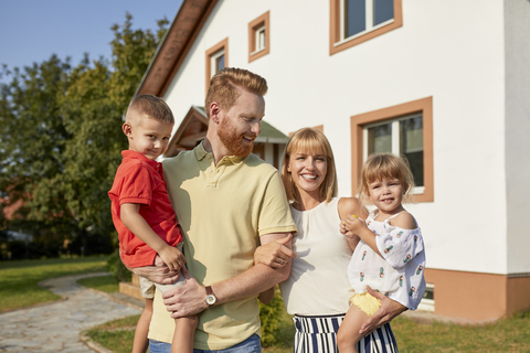 Porträt einer glücklichen Familie im Garten ihres Hauses, lizenzfreies Stockfoto