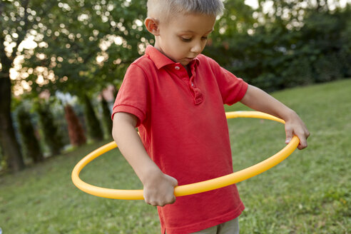 Junge spielt mit Hula-Hoop-Reifen im Garten - ZEDF01557