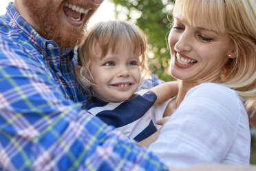 Happy parents hugging her daughter outdoors - ZEDF01563