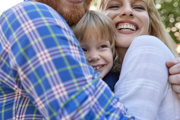 Happy parents hugging her daughter outdoors - ZEDF01564