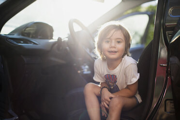 Porträt eines kleinen Jungen auf dem Fahrersitz in einem Auto bei Gegenlicht - AZOF00053