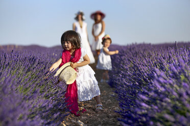 Kleines Mädchen spielt mit lila Blumen, die im Feld wachsen - AURF05585