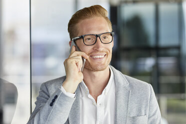 Porträt eines lächelnden rothaarigen Geschäftsmannes am Mobiltelefon - RBF06728
