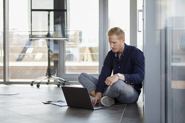 Businessman sitting on the floor using laptop - RBF06730