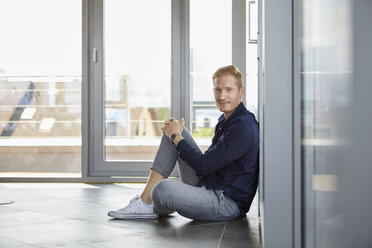 Porträt eines lächelnden Geschäftsmannes, der am Fenster sitzt - RBF06732