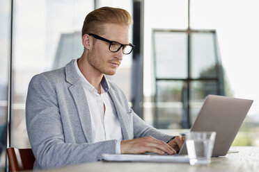 Businessman using laptop on desk in office - RBF06733