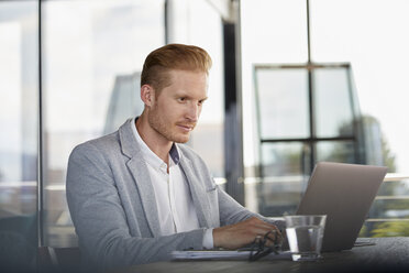 Businessman using laptop on desk in office - RBF06734