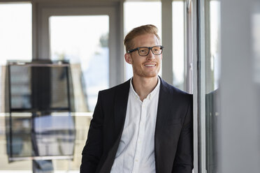 Smiling businessman in office looking out of window - RBF06781