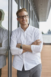 Portrait of smiling businessman leaning against window - RBF06783