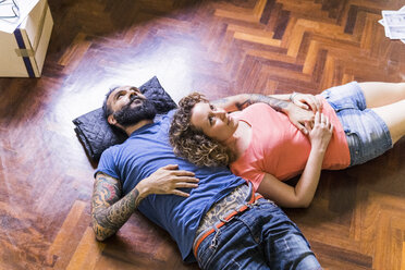 Daydreaming couple lying on the floor of new home - FBAF00044