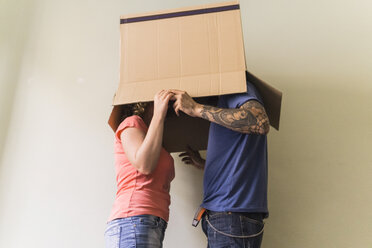 Ehepaar mit zusammengesteckten Köpfen in einem Karton im neuen Zuhause - FBAF00045