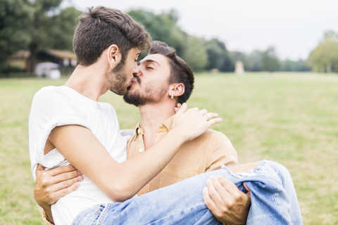 Küssendes junges schwules Paar in einem Park, lizenzfreies Stockfoto