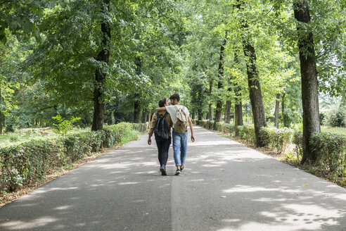 Rückenansicht eines jungen schwulen Paares mit Rucksäcken, das auf einer Straße geht - FBAF00082