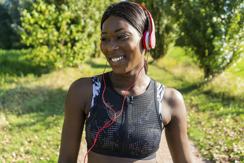 Junger Sportler in der Natur, der mit Kopfhörern Musik hört, lizenzfreies Stockfoto