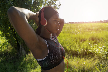 Junger Sportler in der Natur, der mit Kopfhörern Musik hört - GIOF04468