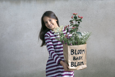Porträt eines glücklichen Mädchens, das eine Papiertüte mit Blumen hält - PSTF00192