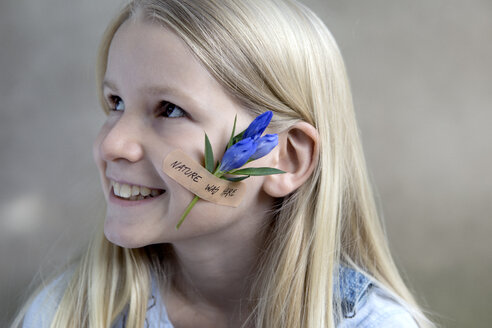 Porträt eines lächelnden blonden Mädchens mit Blumenkopf auf der Wange - PSTF00198