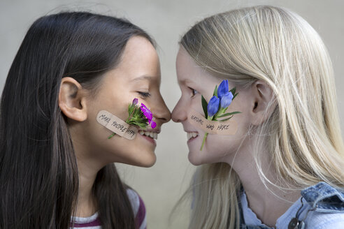 Profile von zwei lächelnden Mädchen mit Blumenköpfen auf den Wangen - PSTF00202