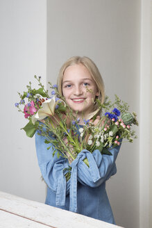 Porträt eines lächelnden blonden Mädchens mit Blumensträußen in den Ärmeln ihres Kleides - PSTF00217