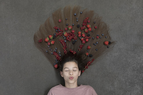 Porträt eines auf dem Boden liegenden Mädchens mit geschlossenen Augen und Früchten im Haar - PSTF00218