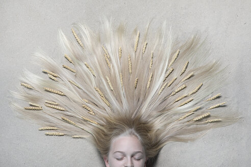 Porträt eines auf dem Boden liegenden Mädchens mit geschlossenen Augen und Weizenähren im Haar - PSTF00222