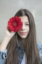 Porträt eines lächelnden Mädchens mit einem Blumenkopf aus roter Gerbera - PSTF00233
