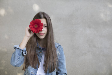 Porträt eines lächelnden Mädchens mit einem Blumenkopf aus roter Gerbera - PSTF00234