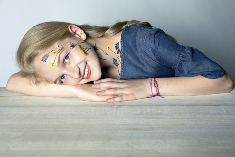 Porträt eines lächelnden blonden Mädchens mit einer Tätowierung aus gepressten Blumen im Gesicht, lizenzfreies Stockfoto