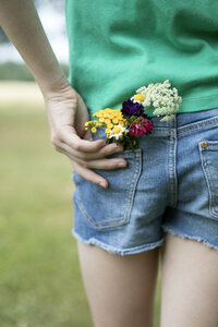 Blumen in der Tasche der Jeans-Shorts eines Mädchens - PSTF00256