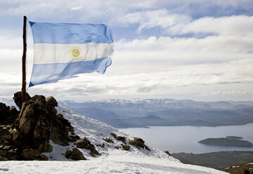 Die argentinische Flagge weht im Wind auf dem Gipfel des Cerro Catedral an einem sonnigen Tag in den Anden - AURF05657