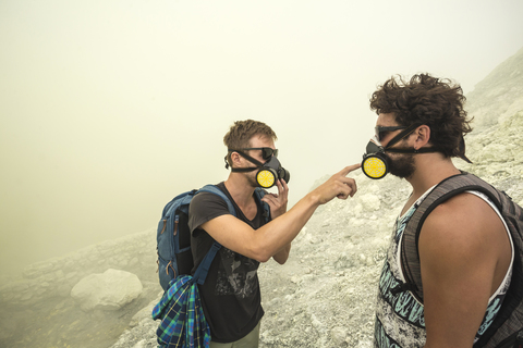Zwei männliche Wanderer überprüfen ihre Luftfilter im Vulkan Kawah Ijen, Java, Indonesien, lizenzfreies Stockfoto