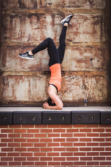Frau macht Übung auf der Spitze der Backsteinmauer - AURF05744