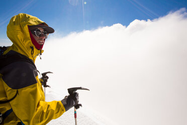 Junger Mann wandert mit Skiausrüstung durch Wolken in den Bergen, Seengebiet, Chile - AURF05752