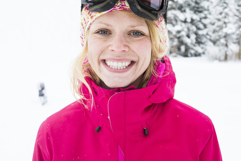 Junge Frau mit strahlendem Lächeln beim Skifahren in den Bergen - AURF05753
