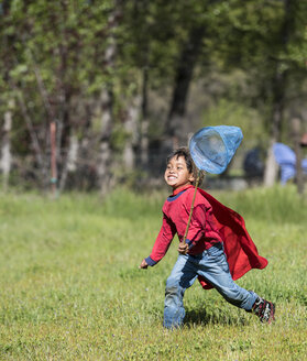 Junger asiatischer Junge jagt Schmetterlinge auf grasbewachsener Landschaft - AURF05795
