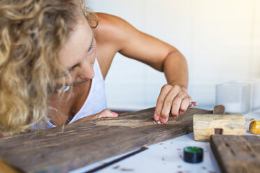 Young woman carves picture on wood - AURF05808