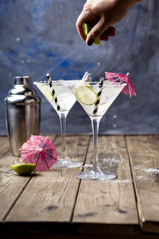 Frauenhand, die eine Limette für einen Margherita-Cocktail auspresst, lizenzfreies Stockfoto