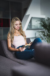 Young woman reading a book on a couch - KKAF01994