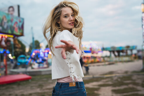 Young woman on a funfair reaching out her hand - KKAF02020