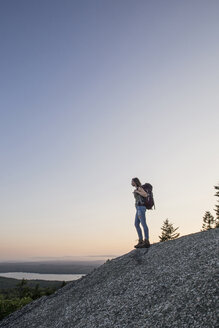 Eine Wanderin genießt die Aussicht bei Sonnenuntergang vom Great Pond Mountain, Maine. - AURF05855