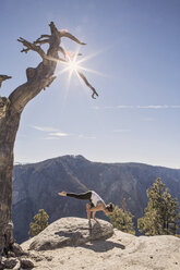 A young woman practices yoga at the top of a cliff in California's Yosemite National Park. - AURF05861