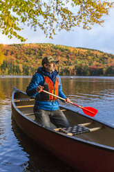 A man canoeing on Greenough Pond in Wentworths Location, New Hampshire. Fall. Northern Forest. - AURF05907